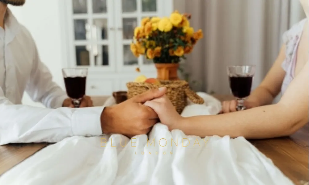 a man and a woman holding hands over a dinner table in a restaurant