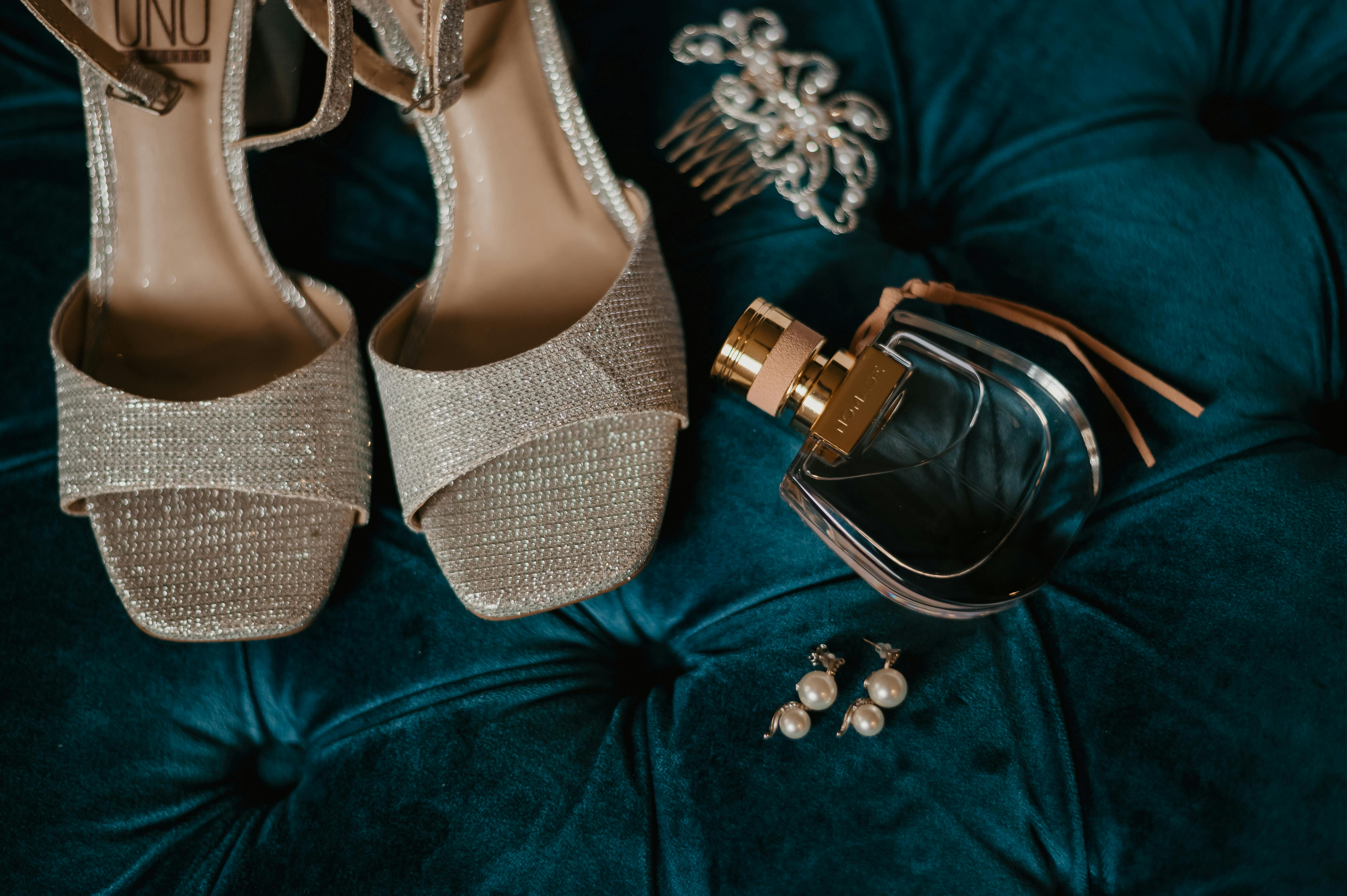 heels, perfume, and jewelry on a velvet cushion